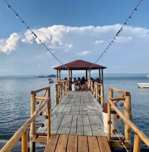 A wooden pier and gazebo reaching out over Lake Bolsena, with the far shore beyond
