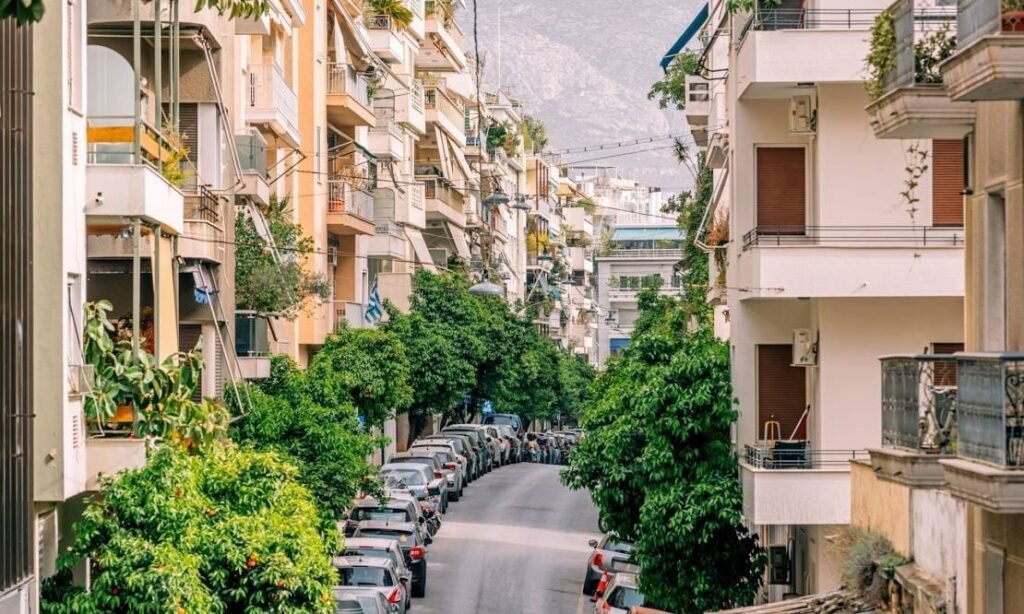 A residential Exarchia street lined with balconied apartment blocks and orange trees.