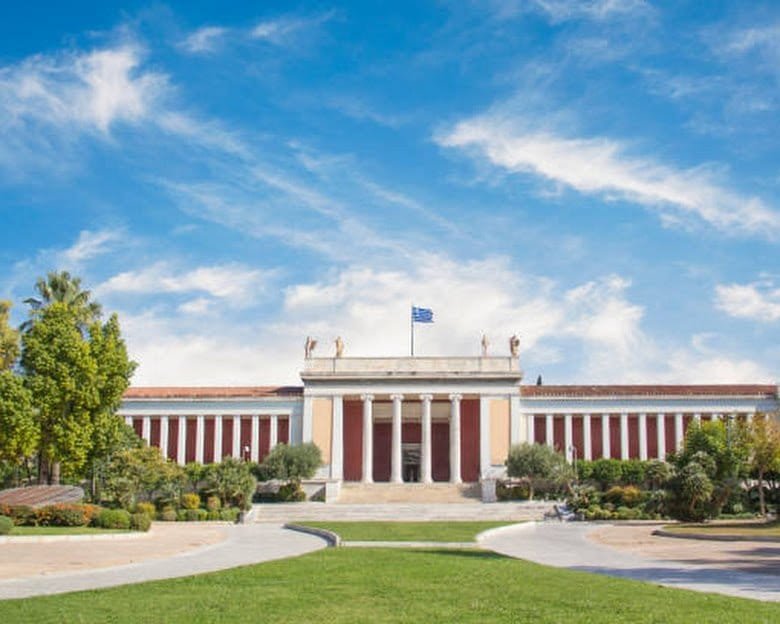The neoclassical colonnade of the National Archaeological Museum in Athens, behind its garden forecourt.