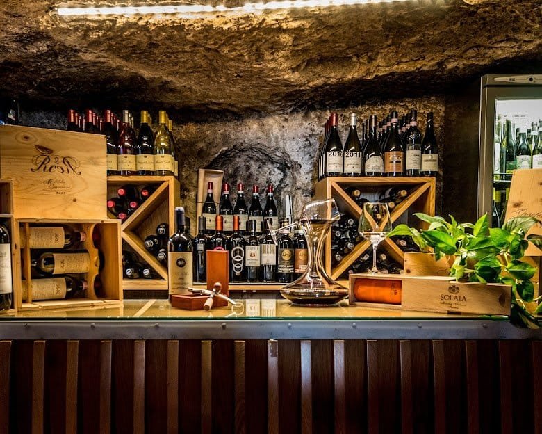 A vaulted stone wine bar, its shelves and crates stacked with Sicilian bottles.