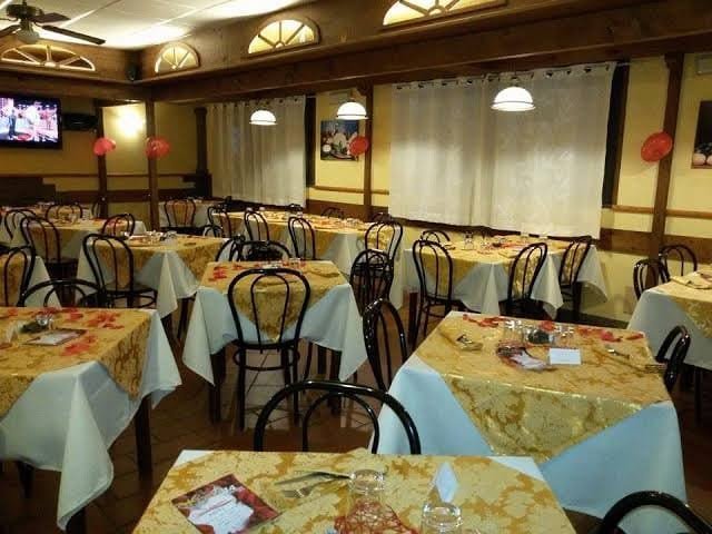 Tables laid with yellow cloths in a traditional dining room, bentwood chairs pushed in.