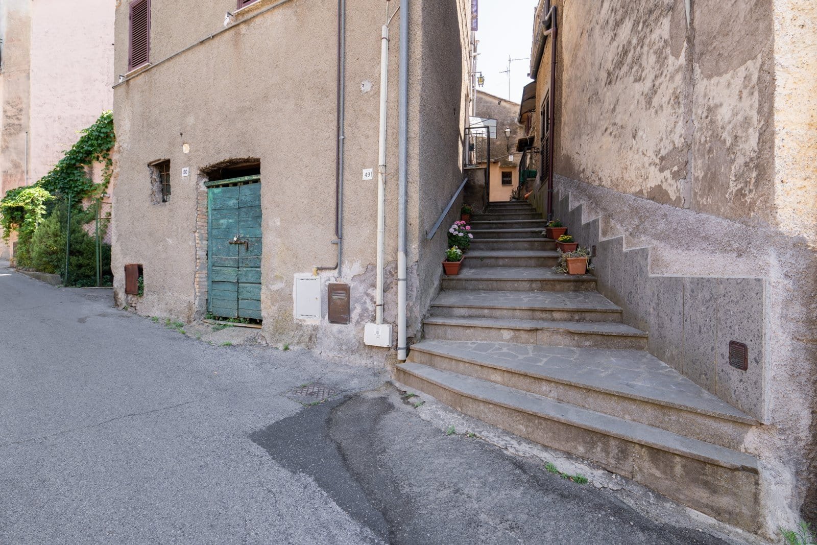 A narrow stone lane in Bassano in Teverina, climbing between tufa walls and shuttered houses.